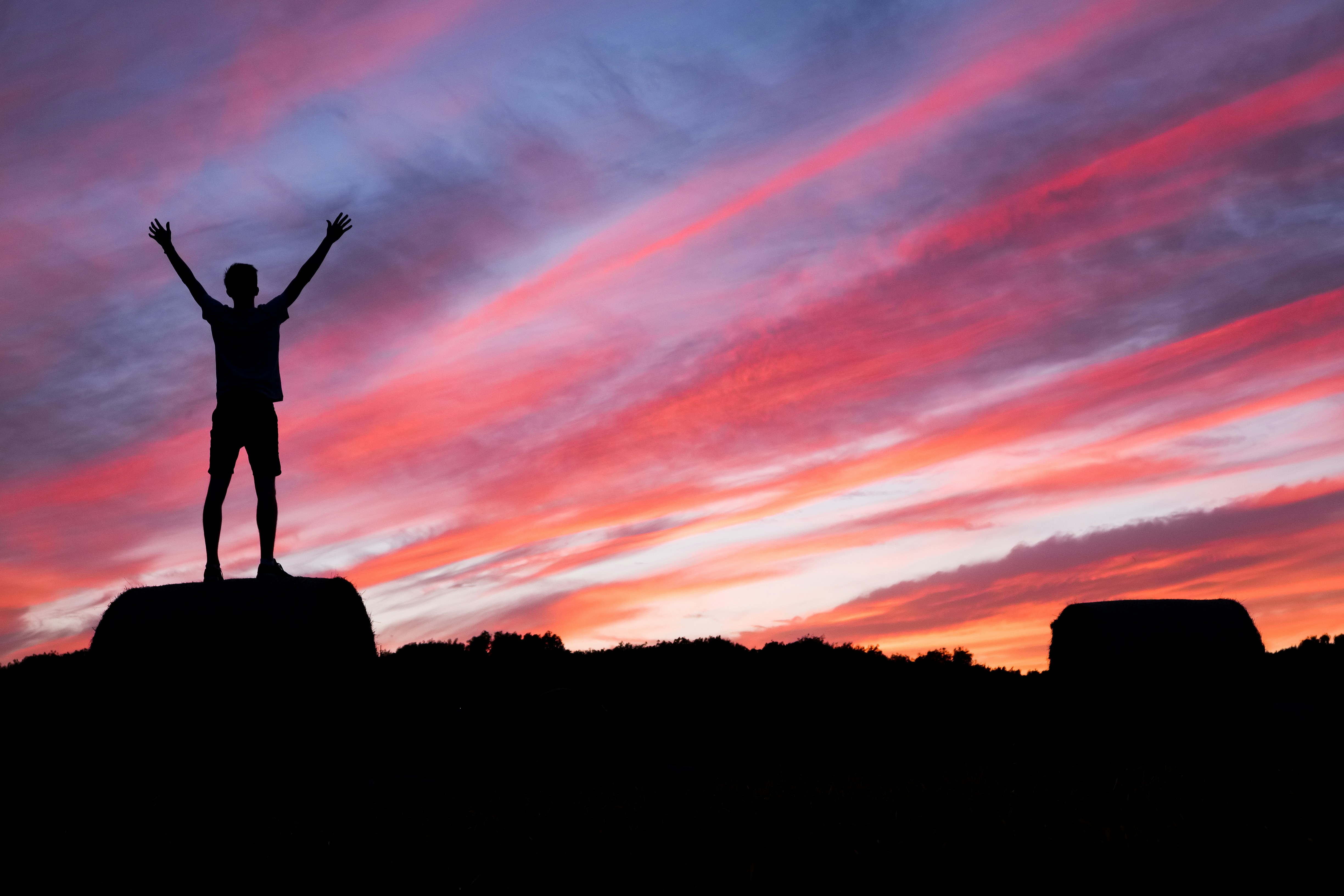 Silhouette eines Menschen bei Sonnenuntergang unter rot-blauem Himmel